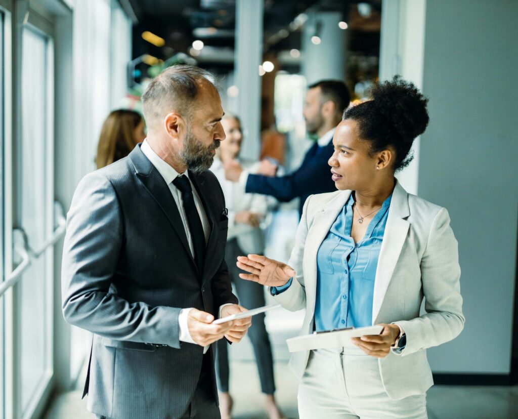 A business man and a business woman speaking in a hallway
